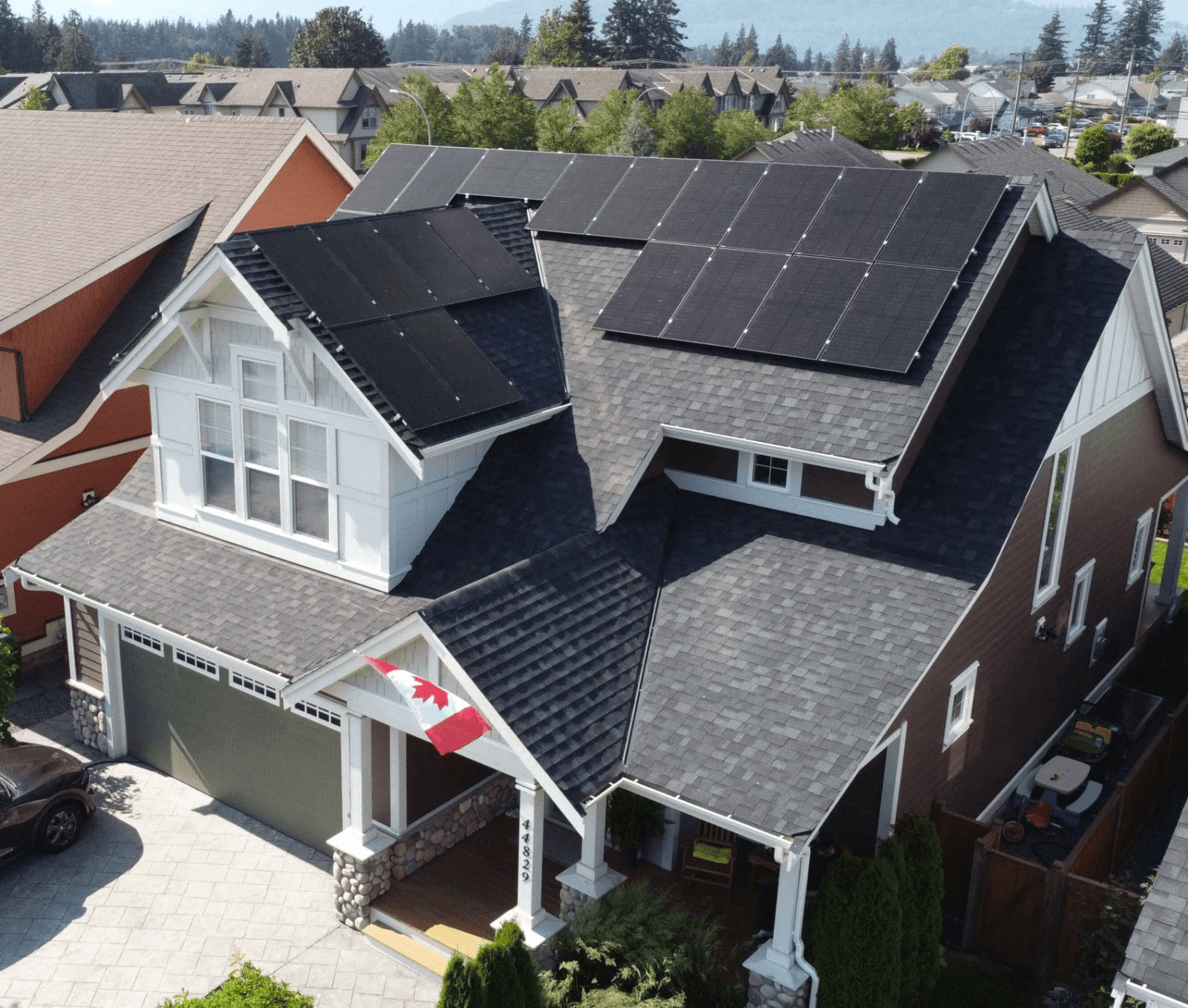 Aerial view of a home with solar panels on the roof and a canadian flag dispalyed on the front porch.